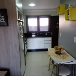 Foto de uma cozinha com armários brancos e bancada escura.