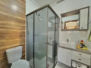 Foto de um banheiro com box de vidro e louças brancas.