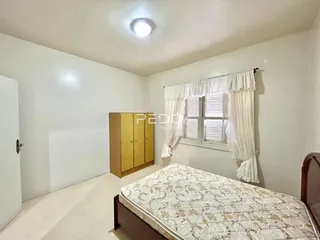 Quarto com janela e armário de madeira em ambiente claro.