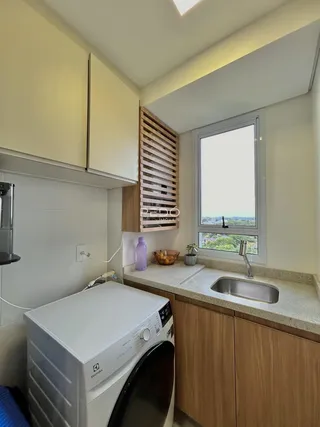 Uma cozinha com armários brancos e madeira e uma janela com vista.