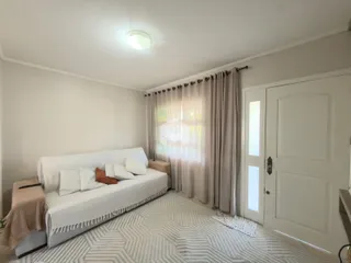 Sala de estar clara com sofá branco e cortinas claras.