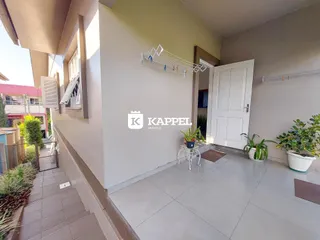Foto do interior de uma sala com piso de porcelanato e plantas decorativas.