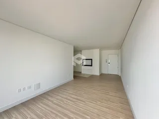Espaço interno com paredes brancas e piso de madeira clara.