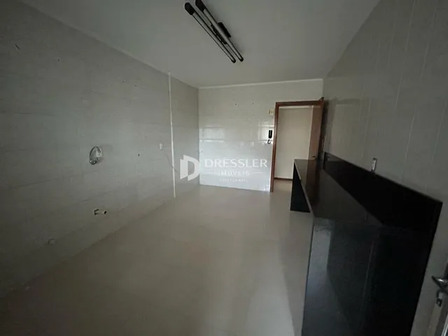 Hall de entrada com paredes brancas e piso claro.