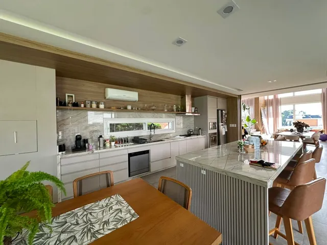 Cozinha e sala de jantar com armários de madeira e bancadas claras.