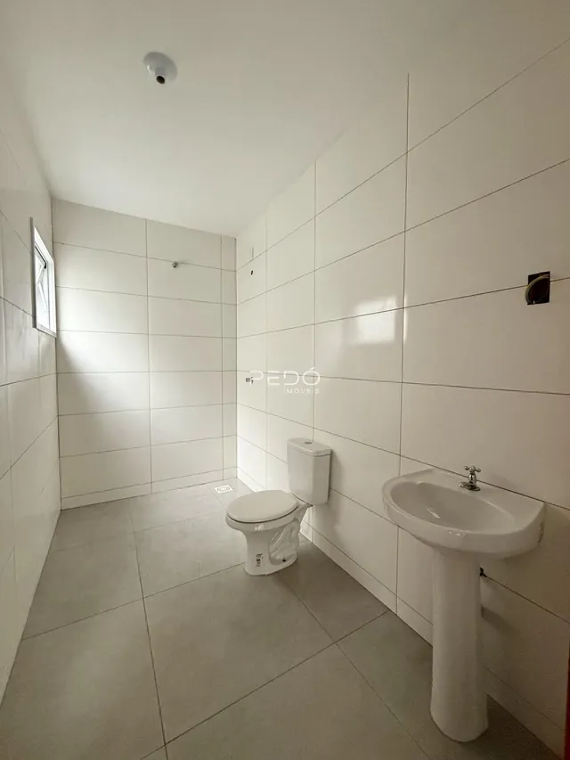 Foto de um banheiro com revestimento de cerâmica branca nas paredes e piso.