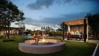 Vista externa de um jardim com área de lazer ao entardecer.