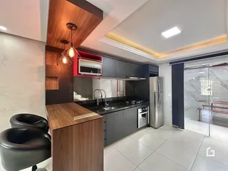Imagem de uma cozinha moderna com armários escuros e eletrodomésticos de aço inoxidável.