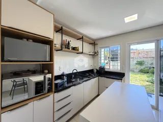 Cozinha moderna com armários brancos e bancadas escuras em um imóvel no Brasil.