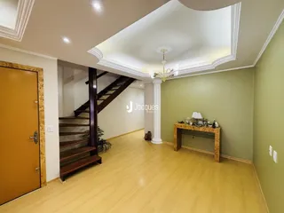 Vista de um hall com escadaria e piso de madeira clara em uma residência.