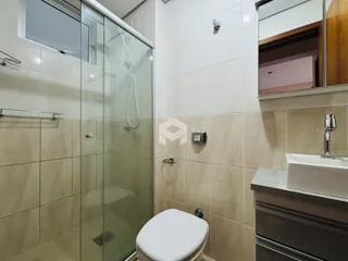 Foto de um banheiro com box de vidro e azulejos claros.
