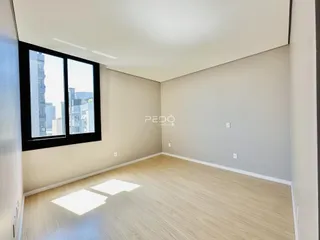Sala de estar com piso de madeira e grande janela.