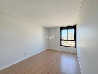 Vista interna de um cômodo com piso de madeira clara e paredes brancas.