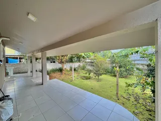 Vista de um pátio externo com piso de cerâmica e jardim gramado.