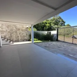 Área externa pavimentada com vista para a vegetação ao lado da residência.
