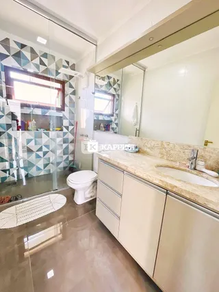 Banheiro com revestimento de azulejos geométricos e bancada clara.