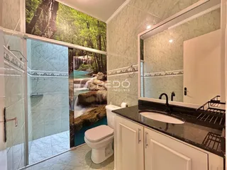 Imagem de um banheiro com revestimento de cerâmica e espelho refletindo uma paisagem de cachoeira.