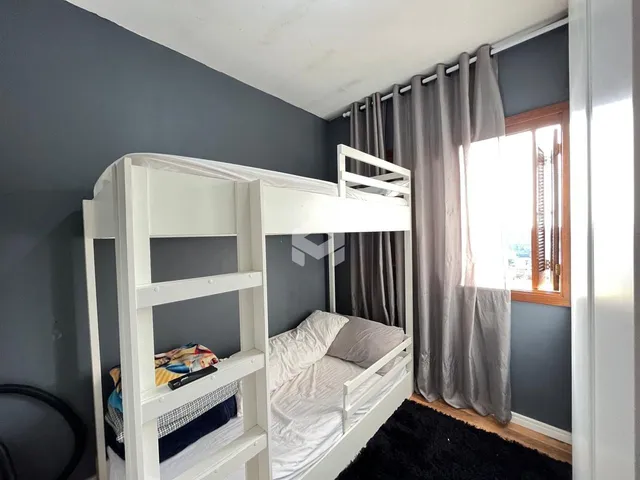 Quarto com cama de beliche branca e paredes cinzas.