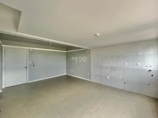 Interior de uma sala ampla com paredes brancas e piso claro.