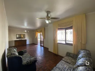 Sala de estar com piso de madeira e cortinas amarelas.