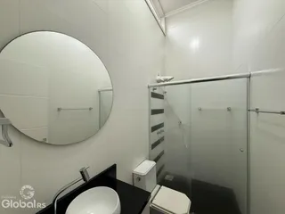Foto de um banheiro moderno com box de vidro e azulejos brancos.