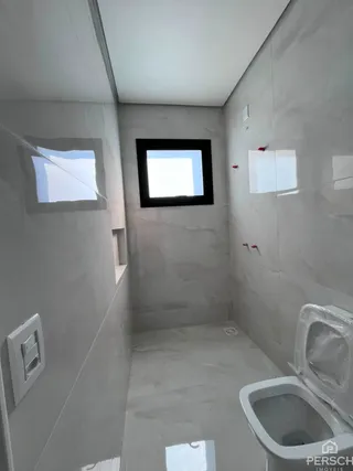 Banheiro com paredes brancas e piso claro.
