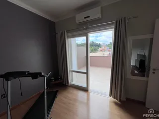 Uma sala de estar com piso de madeira e porta de vidro que dá acesso a uma área externa.
