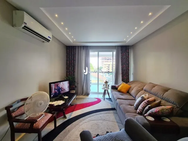 Sala de estar com sofá e televisão em um apartamento.