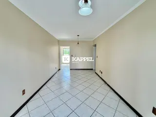 Corredor longo com piso de cerâmica e paredes claras.