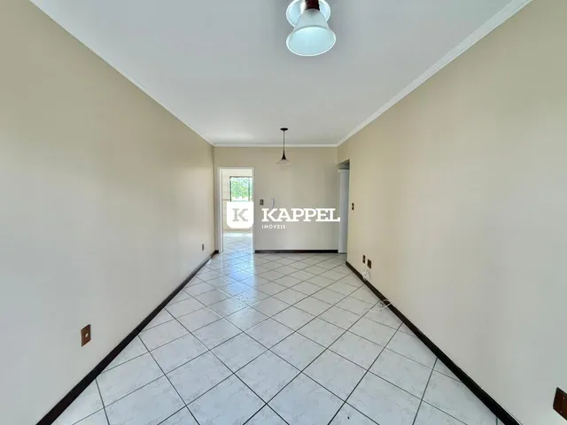 Corredor longo com piso de cerâmica e paredes claras.