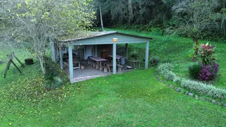Uma estrutura coberta com mesas de madeira está localizada em um jardim verde.