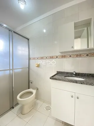 Foto de um banheiro com revestimento cerâmico e bancada branca.