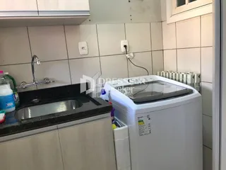 Vista de uma área interna com revestimento de azulejos brancos e uma pia.