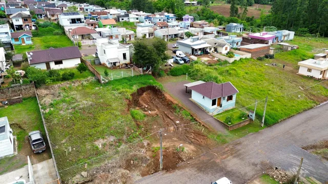 Vista aérea de um terreno com uma casa simples em uma área residencial.