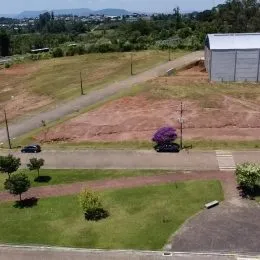 Foto externa mostrando um terreno com área gramada e estrada de terra.