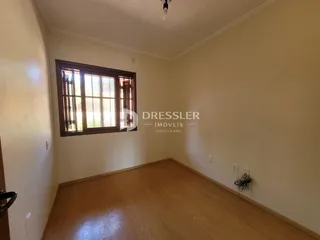 Ambiente interno de uma sala com piso de madeira e janela.