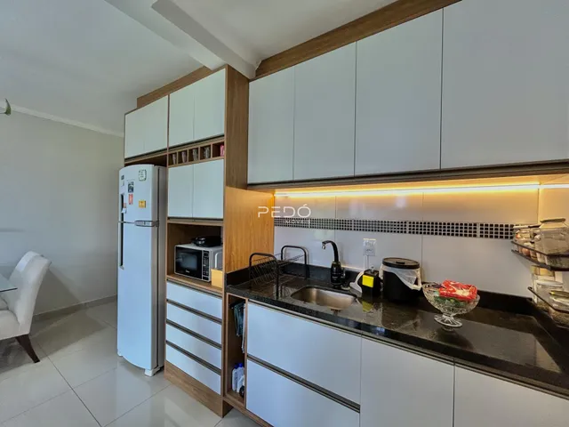 Vista da cozinha moderna com armários brancos e bancadas escuras.