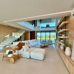 Sala de estar clara com sofá branco e vista para o exterior.