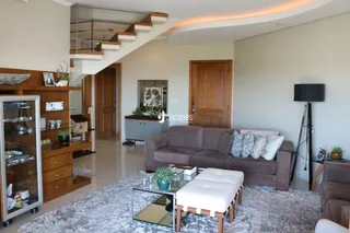 Sala de estar com sofá e escadaria de madeira.