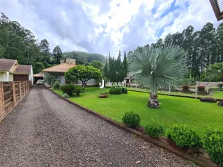 Vista da entrada de uma propriedade com jardim e caminho de cascalho em Lajeado, Brasil.