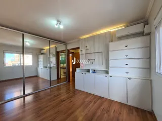 Sala de estar com piso de madeira e armários brancos.