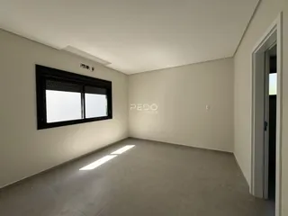 Foto de um ambiente interno vazio com paredes brancas e piso cinza claro.