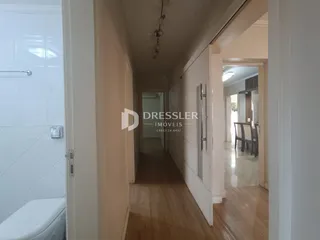 Hall de entrada com piso de madeira e acesso a um banheiro.