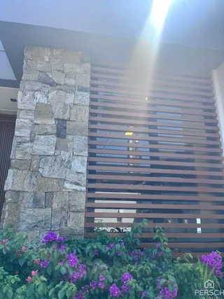 Fachada de uma residência com revestimento de pedra e painéis horizontais.