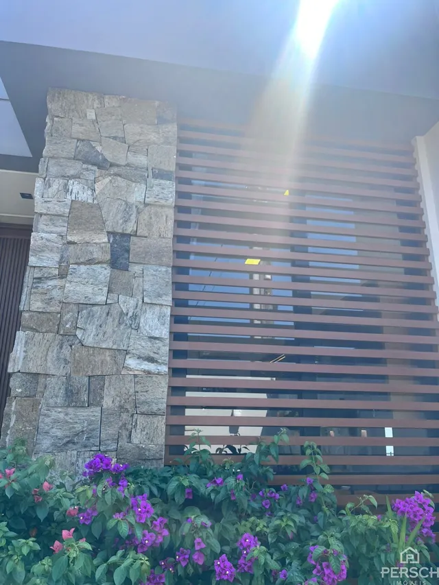 Fachada de uma residência com revestimento de pedra e painéis horizontais.