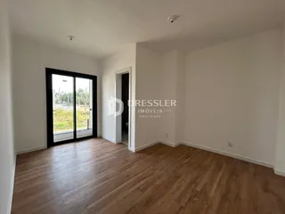 Ambiente interno com piso de madeira e porta de vidro abrindo para o exterior.