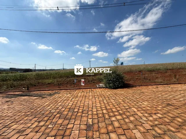 Vista externa de um pátio pavimentado com terra seca ao fundo.