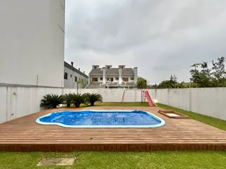 Vista de uma piscina inflável e deck de madeira em um quintal.