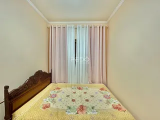 Quarto com cabeceira de madeira e cortinas claras.