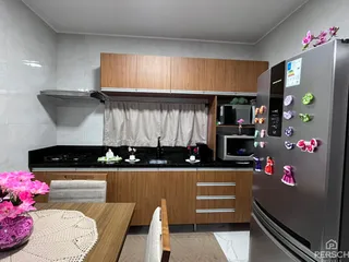 Foto da cozinha com armários de madeira e bancada preta.
